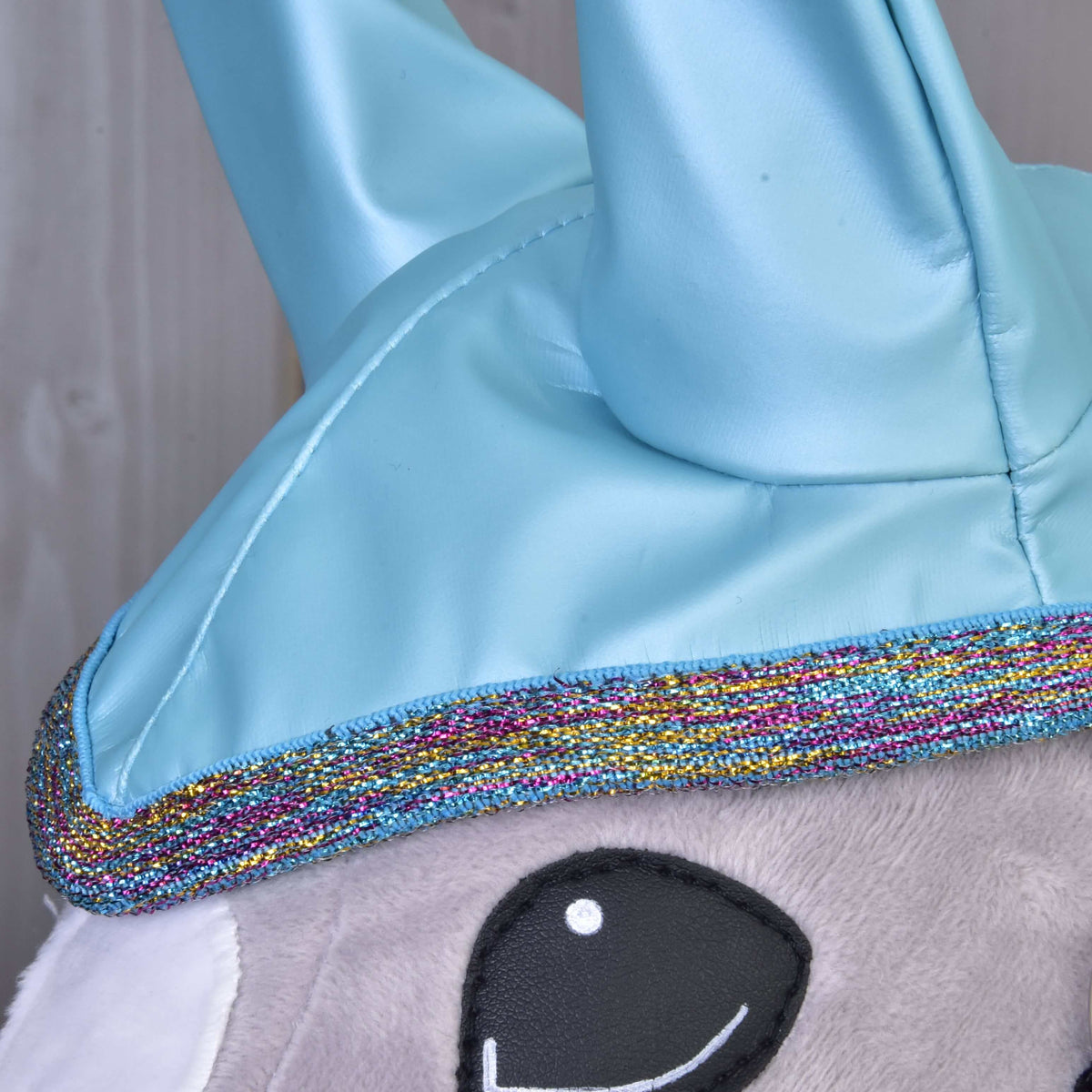 Detail Pláštenka Light Blue od Hobby Horse LarDen s lesklými modrými detailmi, trblietavým viacfarebným lemovaním a mäkkou sivou látkou – ideálny pre Hobby Horse dobrodružstvá za každého počasia.
