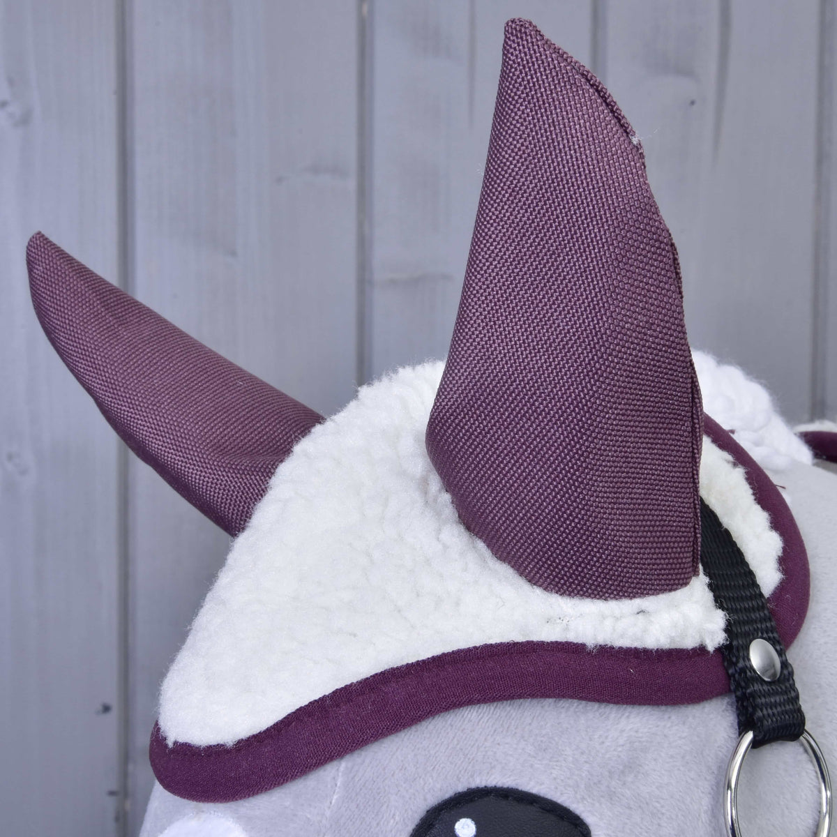 Detail plyšovej zvieracej hlavy Set Loret od Hobby Horse LarDen s bielou chlpatou látkou, veľkými fialovými ušami v štýle čabraky a čiernym pásikom na svetlosivom drevenom pozadí.