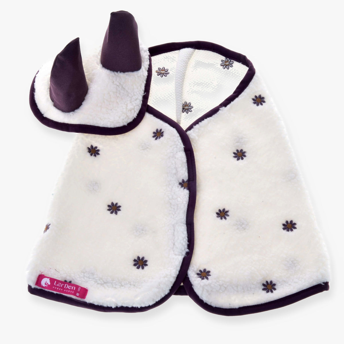 Set Loret od Hobby Horse LarDen je biely fleecový zvierací kostým s fialovým lemom, malými kvetinovými vzormi a kapucňou s dvoma vztýčenými fialovými rohmi, inšpirovaný hravými dizajnmi diek pre Hobby Horse.
