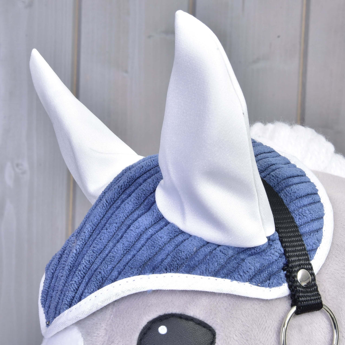 Detail Set Manchester Plum od Hobby Horse LarDen ukazuje biele látkové uši, modrú menčestrovú čabraku, čierny pásik a bielu hrivu na svetlom drevenom pozadí.