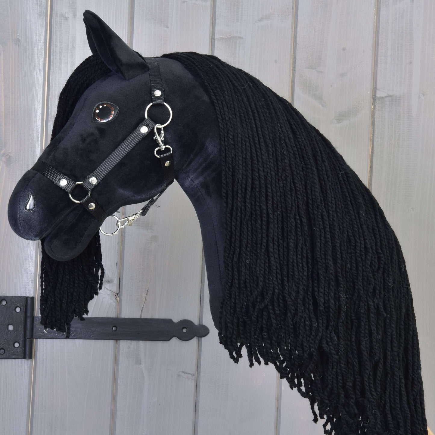 Hobby Horse Maximus s čiernou ohlávkou od Hobby Horse LarDen s ručne vyrábaným dizajnom čierneho žrebca, hustou čiernou priadzovou hrivou a uzdečkou, na svetlom drevenom pozadí.