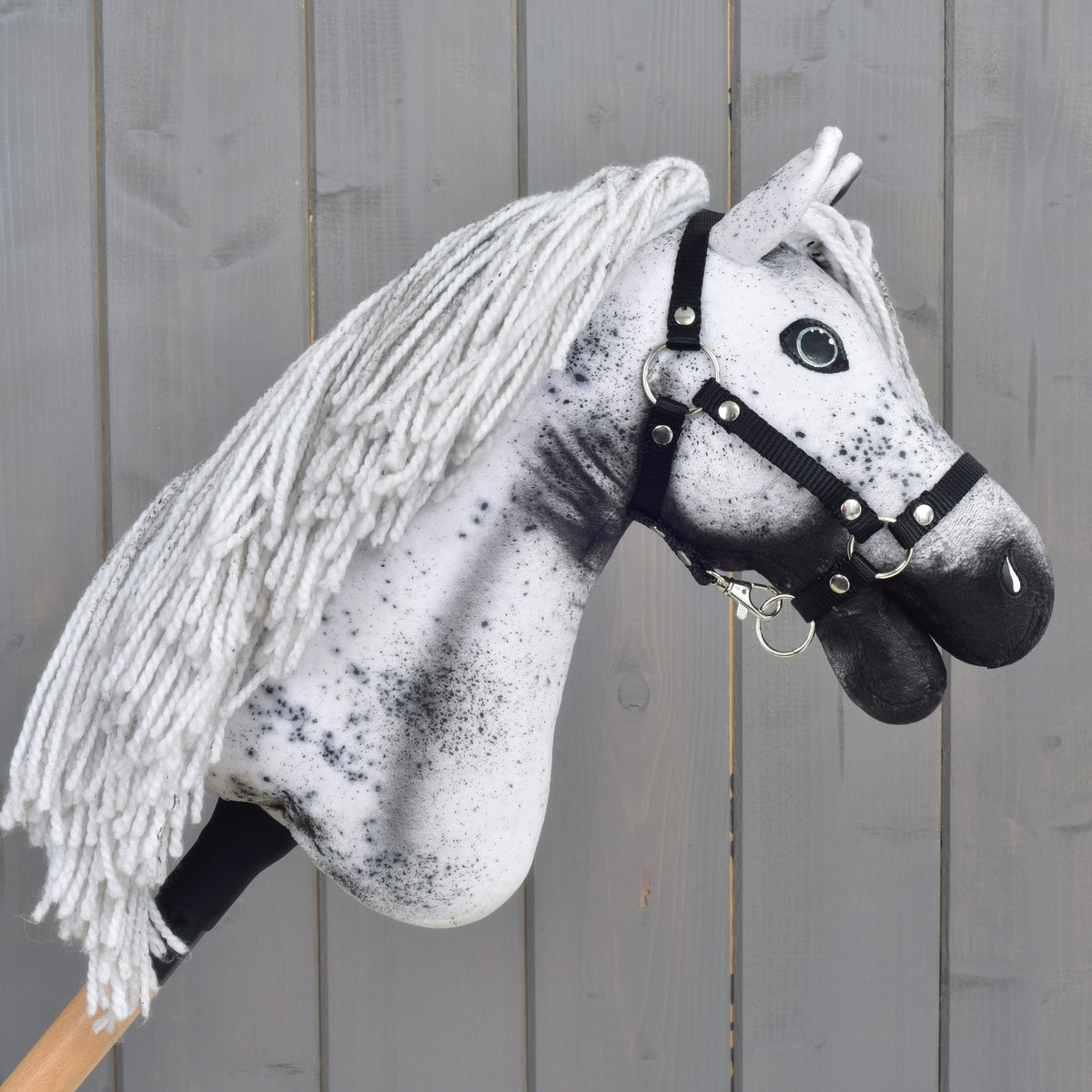 Hobby Horse LarDen "Hobby Horse Naivy with Black Halter" (veľkosť S): ručne vyrobený Hobby Horse vo vzhľade Appaloosy s bielo-sivou priadzovou hrivou, výraznými čiernymi škvrnami a elegantnou čiernou ohlávkou, zasadený do rustikálneho dreveného pozadia. Perfektný pre nápadité dobrodružstvá žrebca!