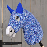 Detail Hobby Horse ochranného obleku See od Hobby Horse LarDen s modro-bílou PES látkou, modrýma ušima a šedým čenichem, nasazeného na dřevěné tyči před šedou dřevěnou stěnou.