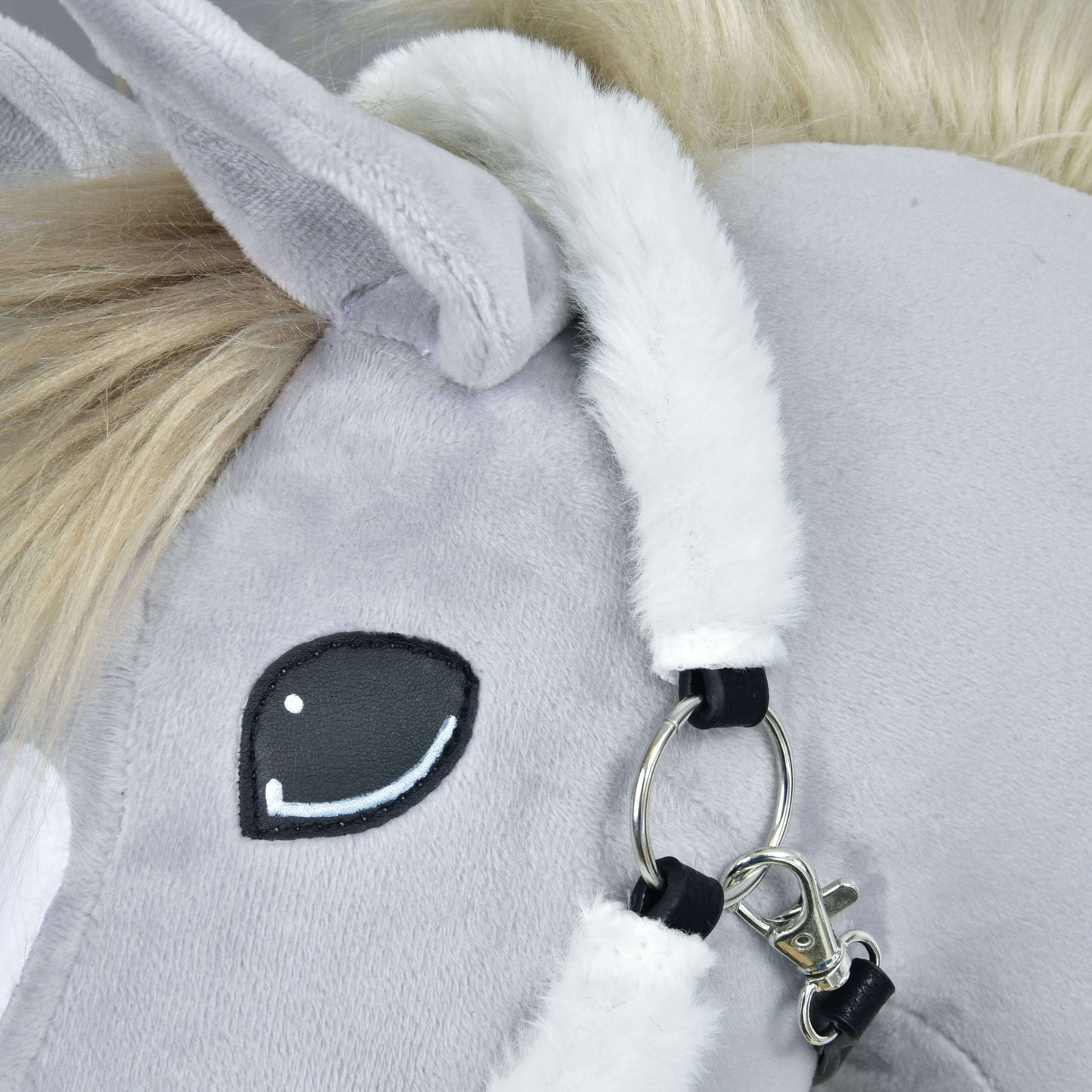 Detail ohlávky s barančekom Teddy Classic od Hobby Horse LarDen: tvár sivého plyšového koňa s čiernobielo vyšitým okom, huňatou bielou hrivou, mäkkým uchom a ohlávkou so strieborným krúžkom a zapínaním.