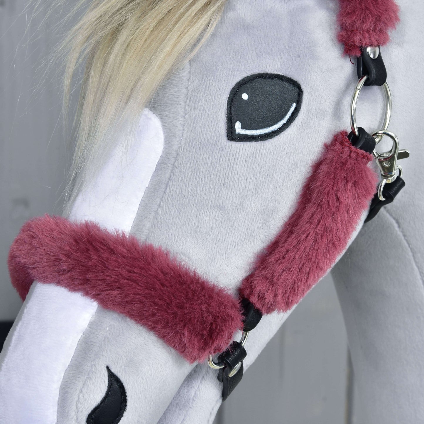 Detail sivého plyšového Hobby Horse LarDen s ohlávkou s barančekom Teddy Maroon, s vínovou barančekovou ohlávkou, bielou hrivou, vyšitými očami a bielou lysinou. Pozadie je rozostrené.