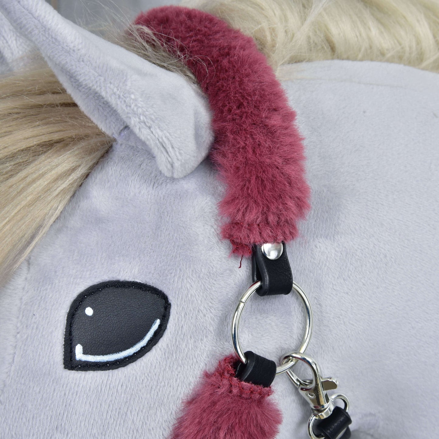 Detail sivého plyšového koňa od Hobby Horse LarDen s ohlávkou s barančekom Teddy Maroon s mäkkým polstrovaním a kovovými krúžkami, bielou hrivou a jednoduchým vyšitým čiernym okom.