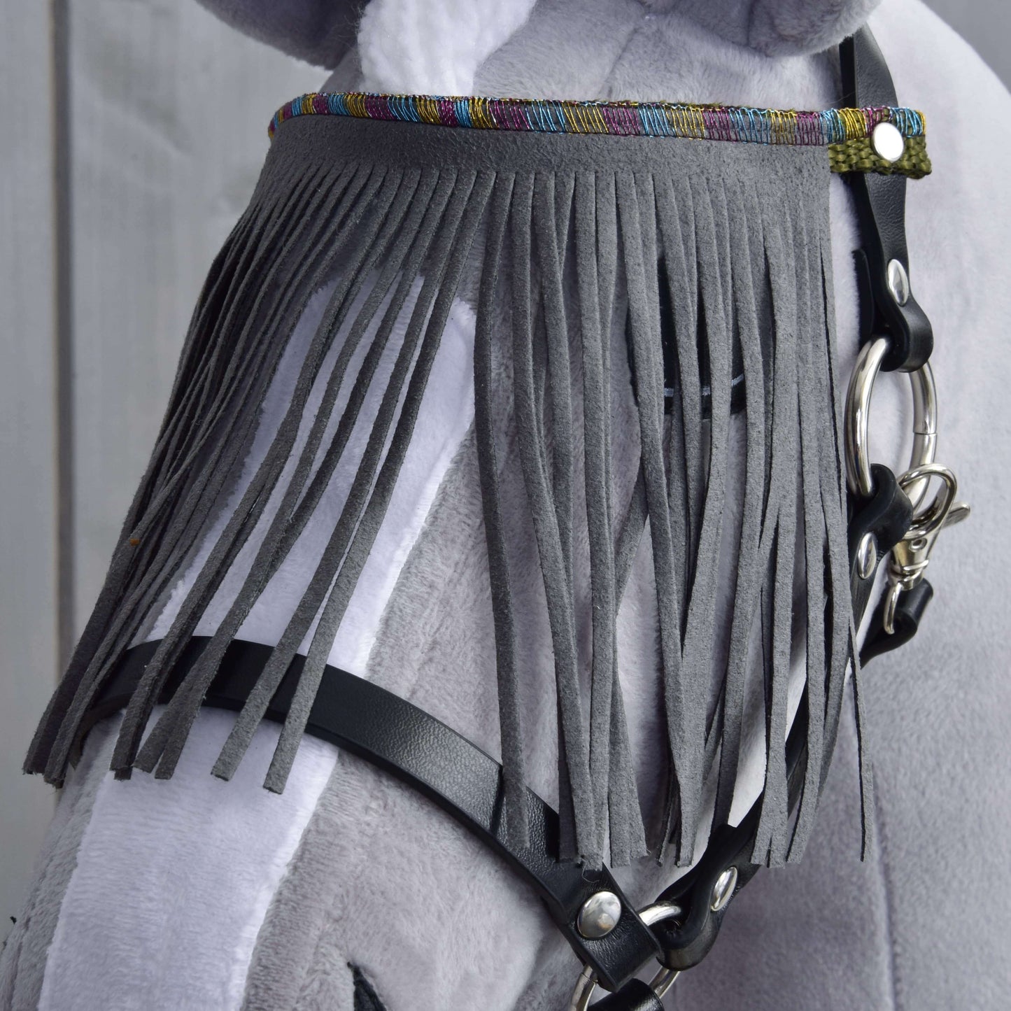 Detail svetlosivobieleho koňa s Ohlávkou čiernou so sivými strapcami od Hobby Horse LarDen, s dlhými zvislými strapcami cez čelo a farebným lemom hore.