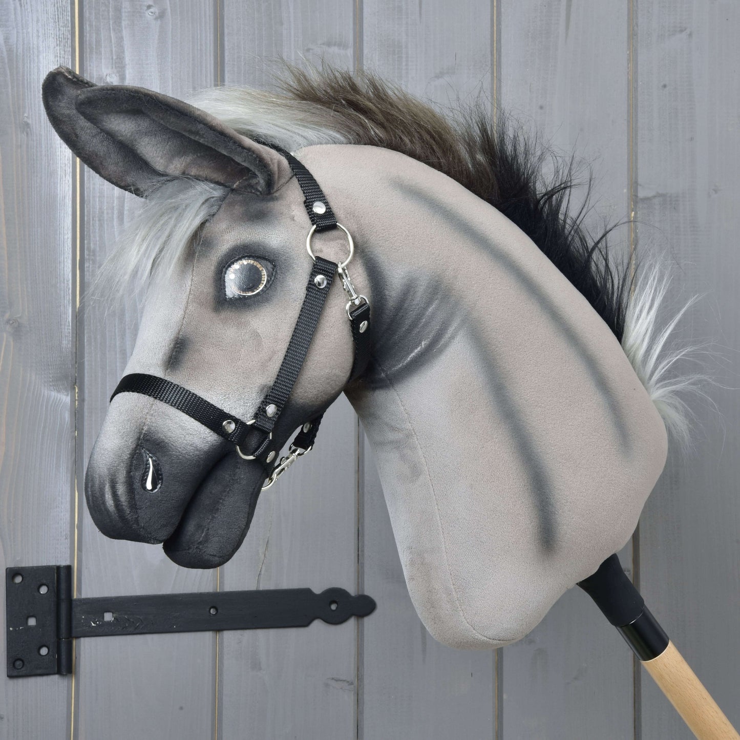Hobby Horse osol Olin s čiernou ohlávkou od Hobby Horse LarDen so sivým plyšovým telom, huňatou hrivou a čiernou ohlávkou, nasadený na drevenej tyči, ideálny na hranie alebo vystavenie na akomkoľvek pozadí.