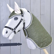 Set Olivetti od Hobby Horse LarDen tvorí sivý Hobby Horse so zelenou prešívanou dekou a uzdečkou, čiernou ohlávkou, bielymi ušami a štýlovými doplnkami, zobrazený pred svetlosivou drevenou stenou.