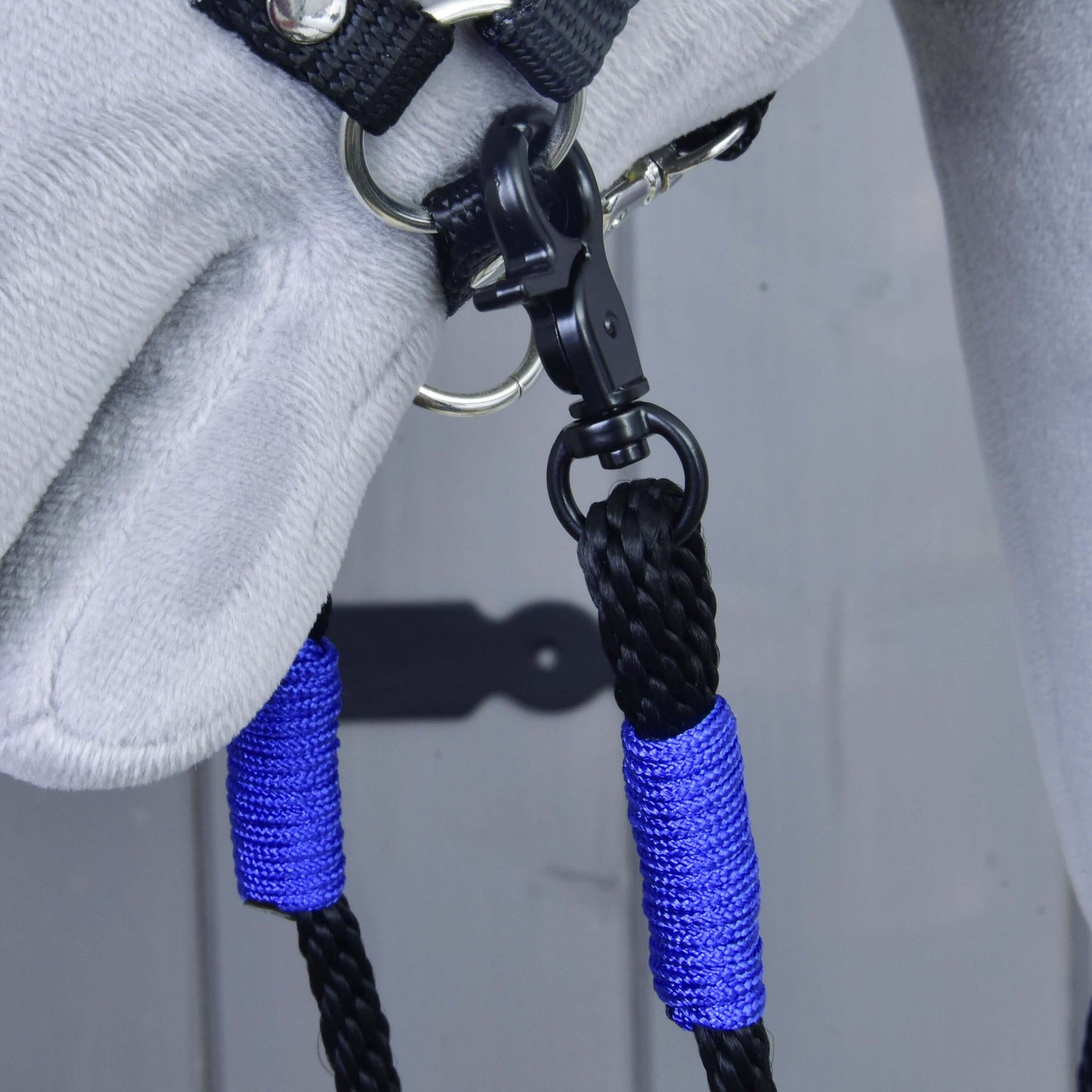 Detail sivej konskej hlavy v čiernej ohlávke s opratami Basic Blue od Hobby Horse LarDen – modro-čierne pletené ručne vyrábané polypropylénové opraty pripevnené ku kovovému krúžku čiernou karabínou.