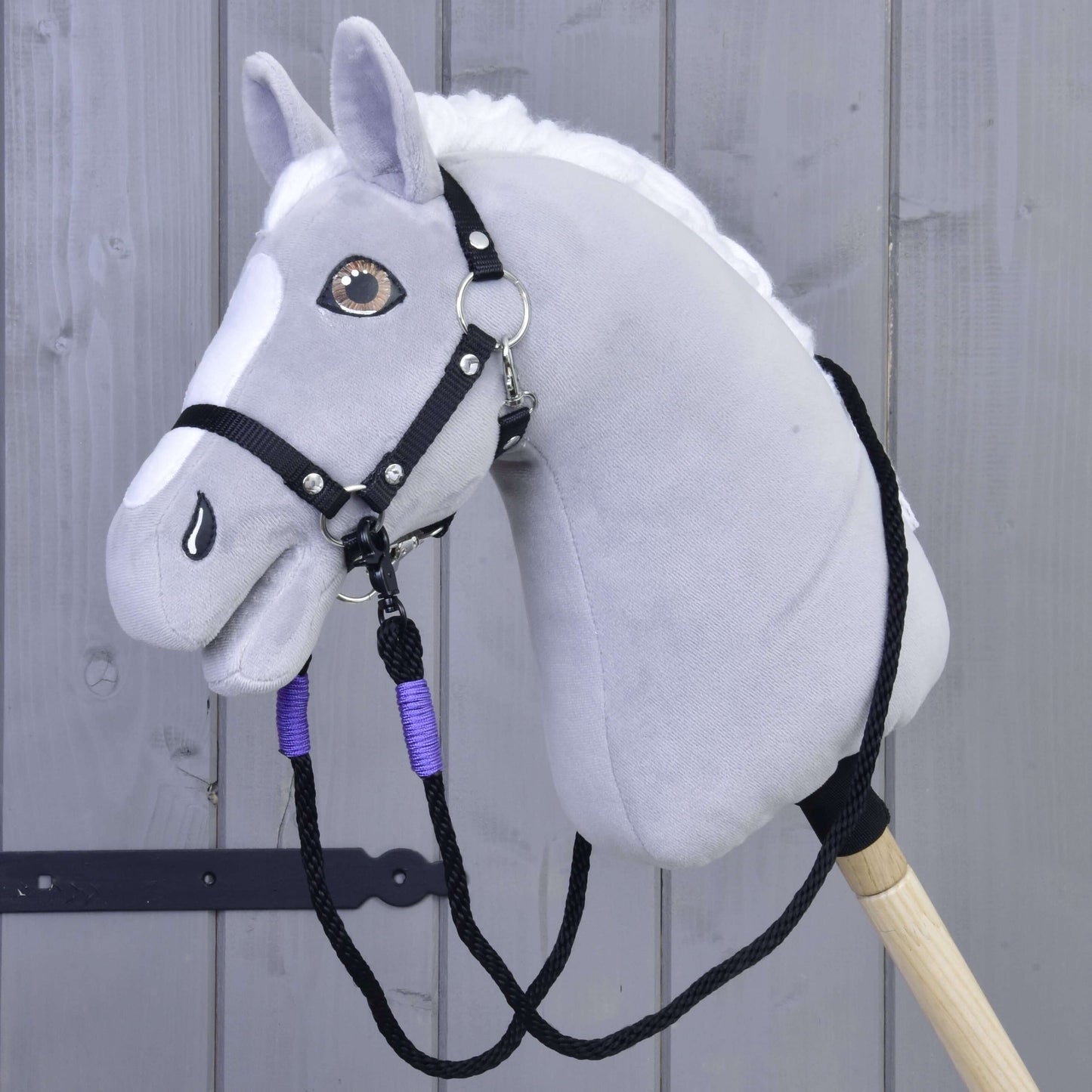 Opraty Basic Lila od Hobby Horse LarDen, ručne vyrobené z polypropylénového lana, zobrazené so sivým plyšovým Hobby Horse s bielou hrivou a čiernou uzdečkou, upevneným na drevenej tyči pred sivým dreveným plotom.
