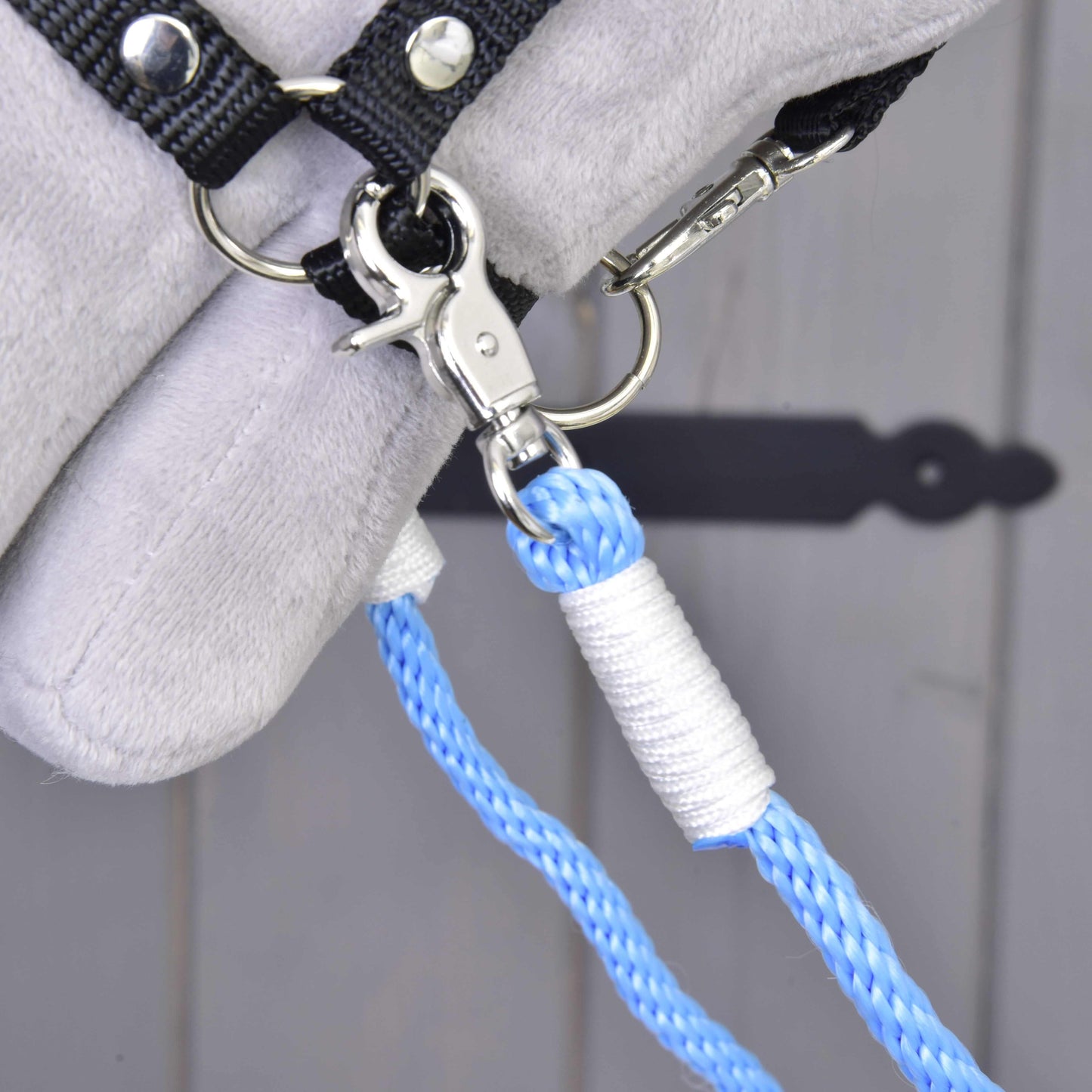 Detail Oprát Sky od Hobby Horse LarDen, modré vodidlo z polypropylénového lana s kovovou karabínou na čiernom háčiku, na pozadí so svetlosivým mäkkým materiálom.