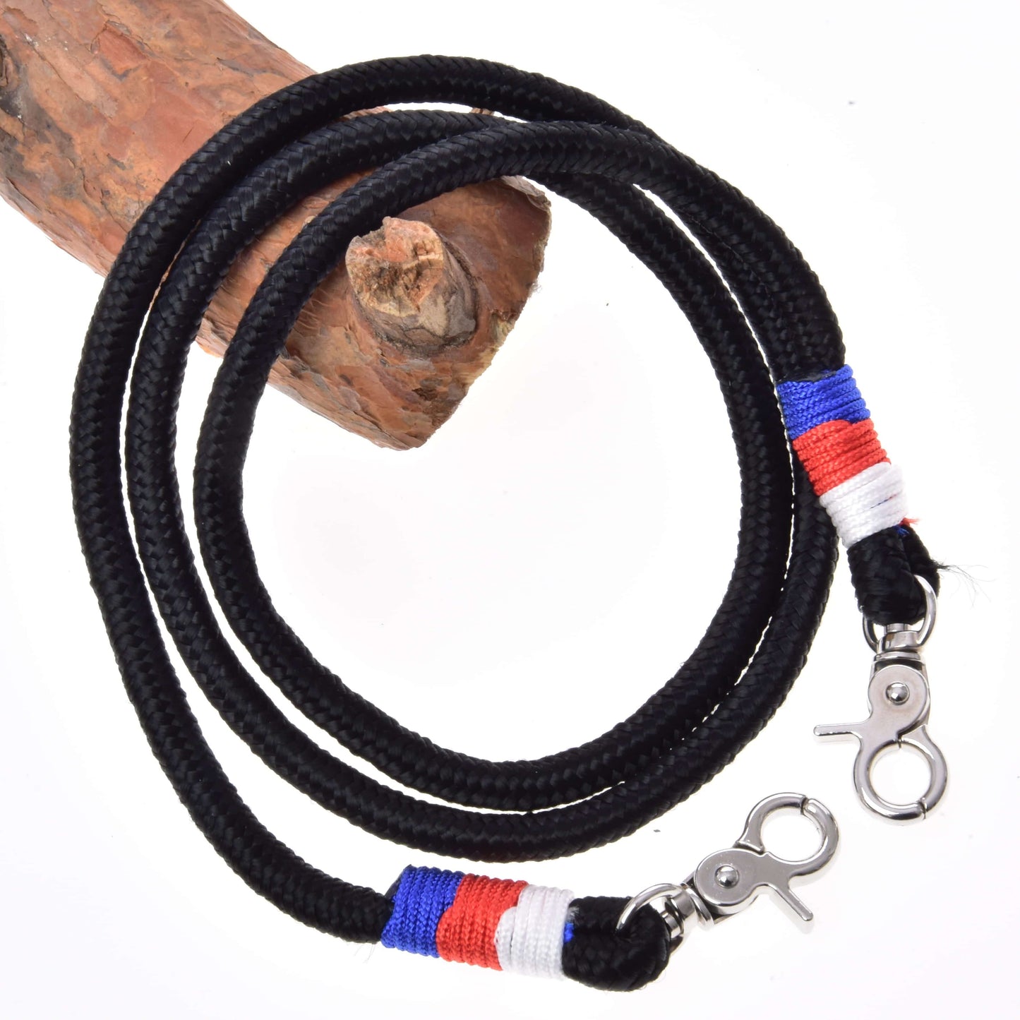 Otěže Emblem CZ od Hobby Horse LarDen, černá pletená šňůra z polypropylenového lana s kovovými karabinami a červenými, modrými a bílými nitěnými akcenty u karabin, stočená kolem dřeva na bílém pozadí.