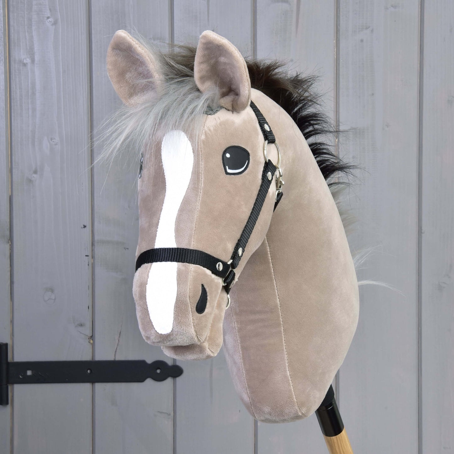 Hobby Horse Piccolino s čiernou ohlávkou od Hobby Horse LarDen, béžový plyšový Hobby Horse s bielou lysinou, čiernymi gombíkovými očami, čiernou hrivou a uzdečkou na drevenej tyči – ideálny pre predstieranú drezúru.
