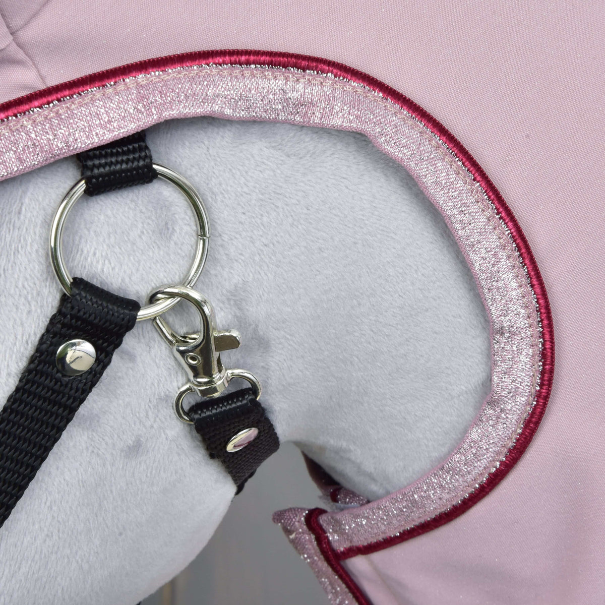 Detail bieleho plyšového zvieraťa v ružovej Pláštenke Veloria od Hobby Horse LarDen s trblietavým lemovaním, s čiernym vodidlom pripnutým k striebornému krúžku a zapínaniu.