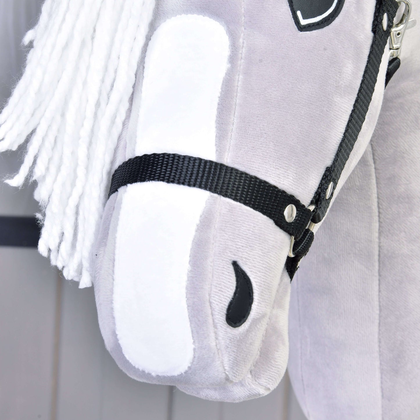 Detail sivého plyšového Hobby Horse Popcorn s čiernou ohlávkou od Hobby Horse LarDen, inšpirovaného anglickým plnokrvníkom, s bielou priadzovou hrivou, čiernou ohlávkou a jemnými šitými detailmi vrátane čiernej nozdry.