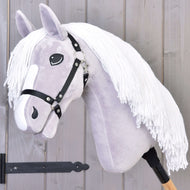 Hobby Horse Popcorn s černou ohlávkou od Hobby Horse LarDen, se světle šedou hlavou, bílou přízovou hřívou, černou ohlávkou a dřevěnou tyčí. Ideální pro nápaditou hru a rodinná koňská dobrodružství. Zobrazené před dřevěnou stěnou.