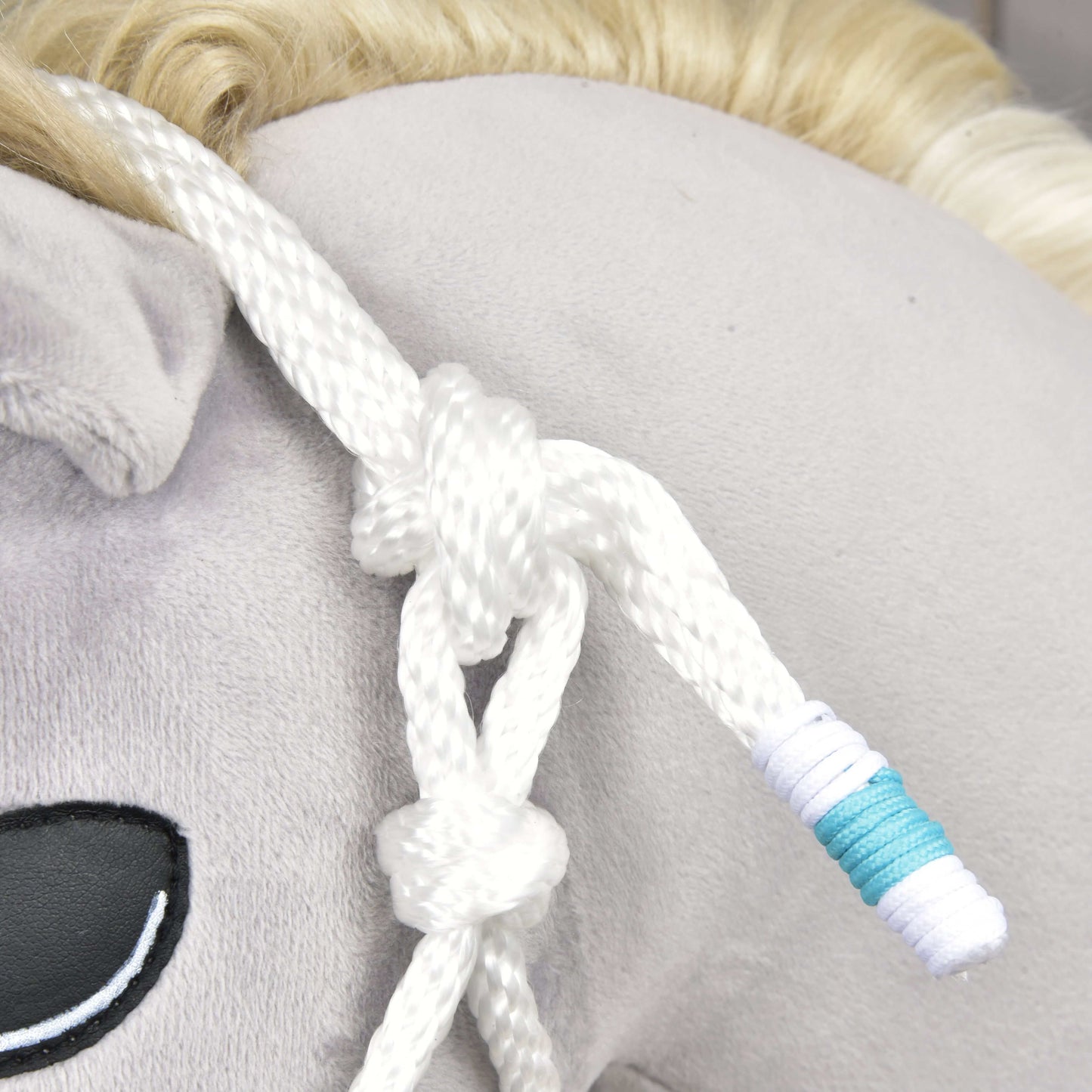 Detail Hobby Horse LarDen so svetlosivou látkou, čierne vyšitým okom, svetlou blond hrivou a Povrazovým setom White Queen – bielou povrazovou ohlávkou zviazanou a omotanou modrobielou niťou.