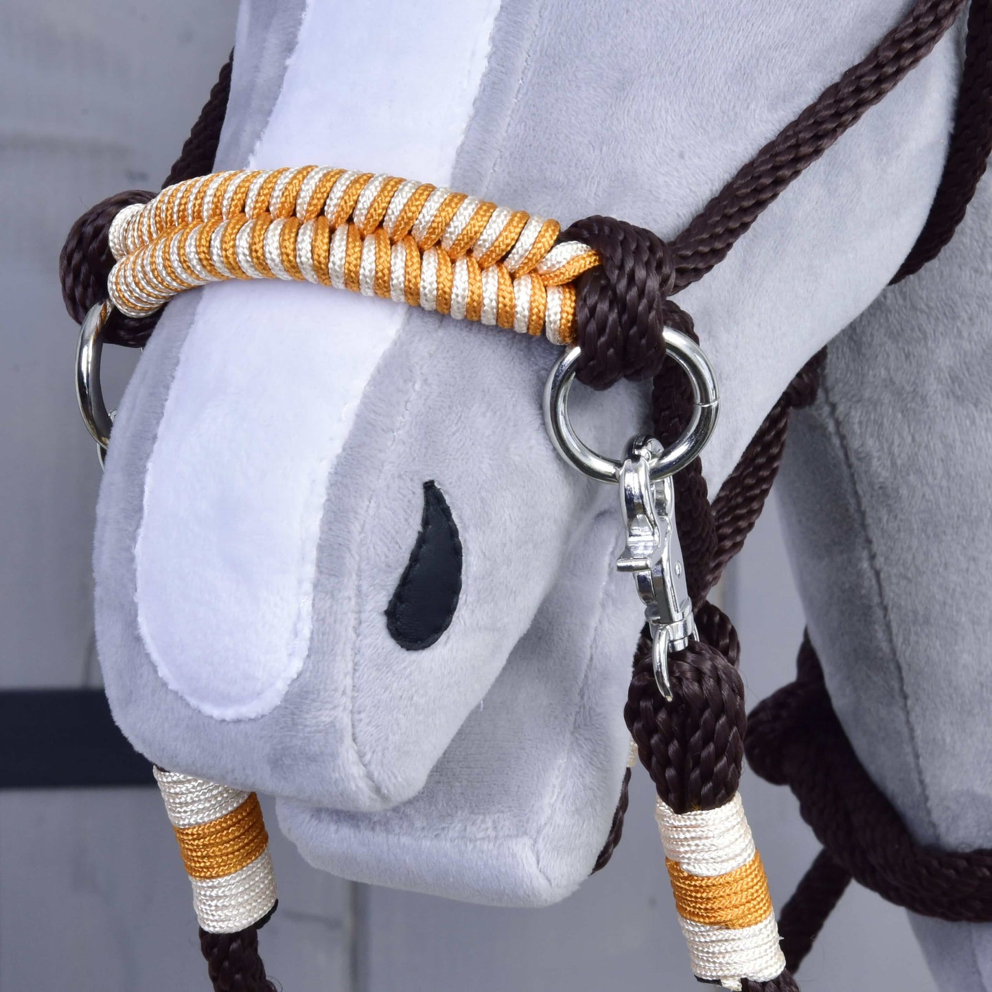 Povrazový set Orange od Hobby Horse LarDen, detail hlavy sady s uzdečkou v oranžovej farbe, strieborným kovaním a ladiacimi oranžovými opratami. Plyšová hračka má sivú tvár, biely pruh na nose a čiernu oválnu nozdru.