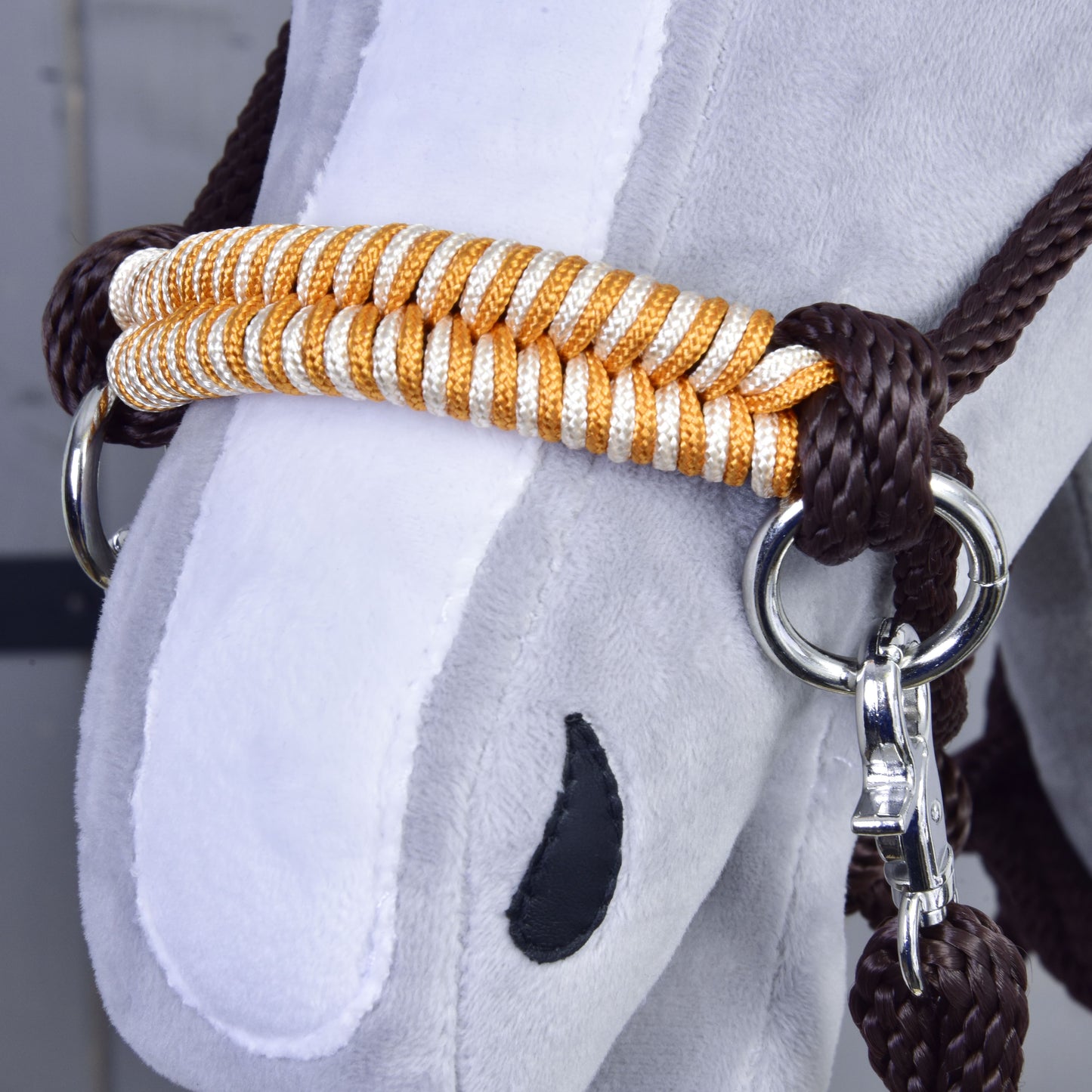 Povrazový set Orange, detail plyšovej tváre Hobby Horse LarDen s bielym ňufákom, čiernou nozdrou a bielo-zlatou ohlávkou s lesklými kovovými krúžkami a ladiacimi hnedými opratami.