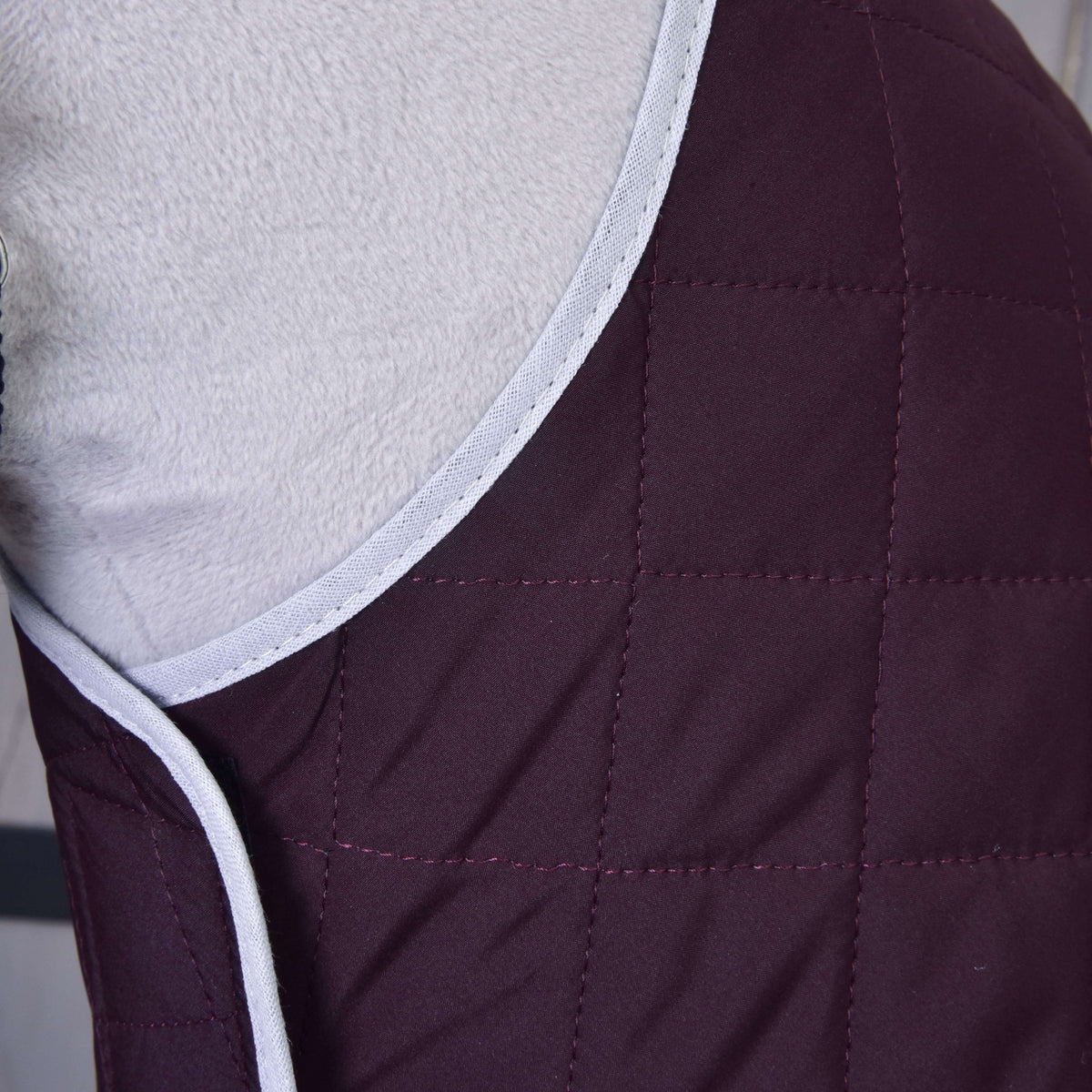 Set Purple od Hobby Horse LarDen – detail prešívanej vínovej látky so svetlosivým lemom, prehodenej cez mäkký povrch. Ideálna ako útulná deka alebo pre dodatočnú ochranu koňa.