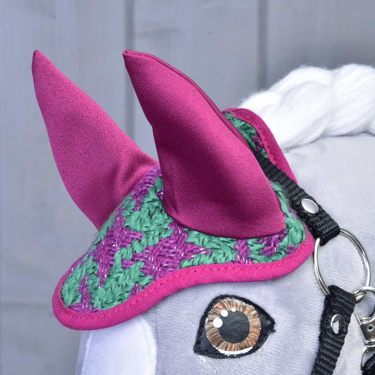 Detail Set Coco od Hobby Horse LarDen: sivá hlava s háčkovanou zeleno-fialovou čabrakou na uši, veľkými ružovými látkovými ušami, bielou hrivou a čiernou uzdečkou s lesklým kovovým krúžkom.