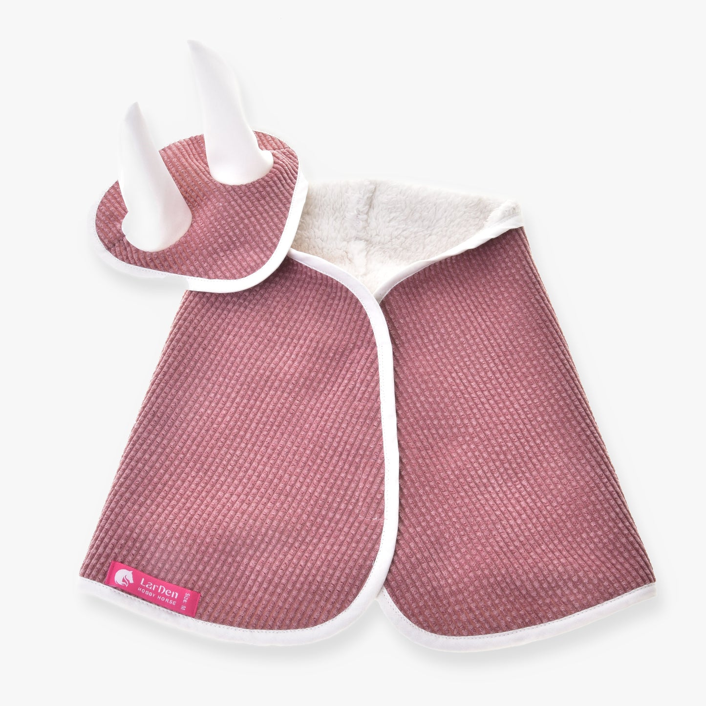 Set Manchester Tea Rose od Hobby Horse LarDen: růžový texturovaný kostým pro mazlíčka s bílým lemem, včetně pláštěnky a čelenky na hlavu s čabrakou na uši a dvěma bílými rohy, na bílém pozadí.