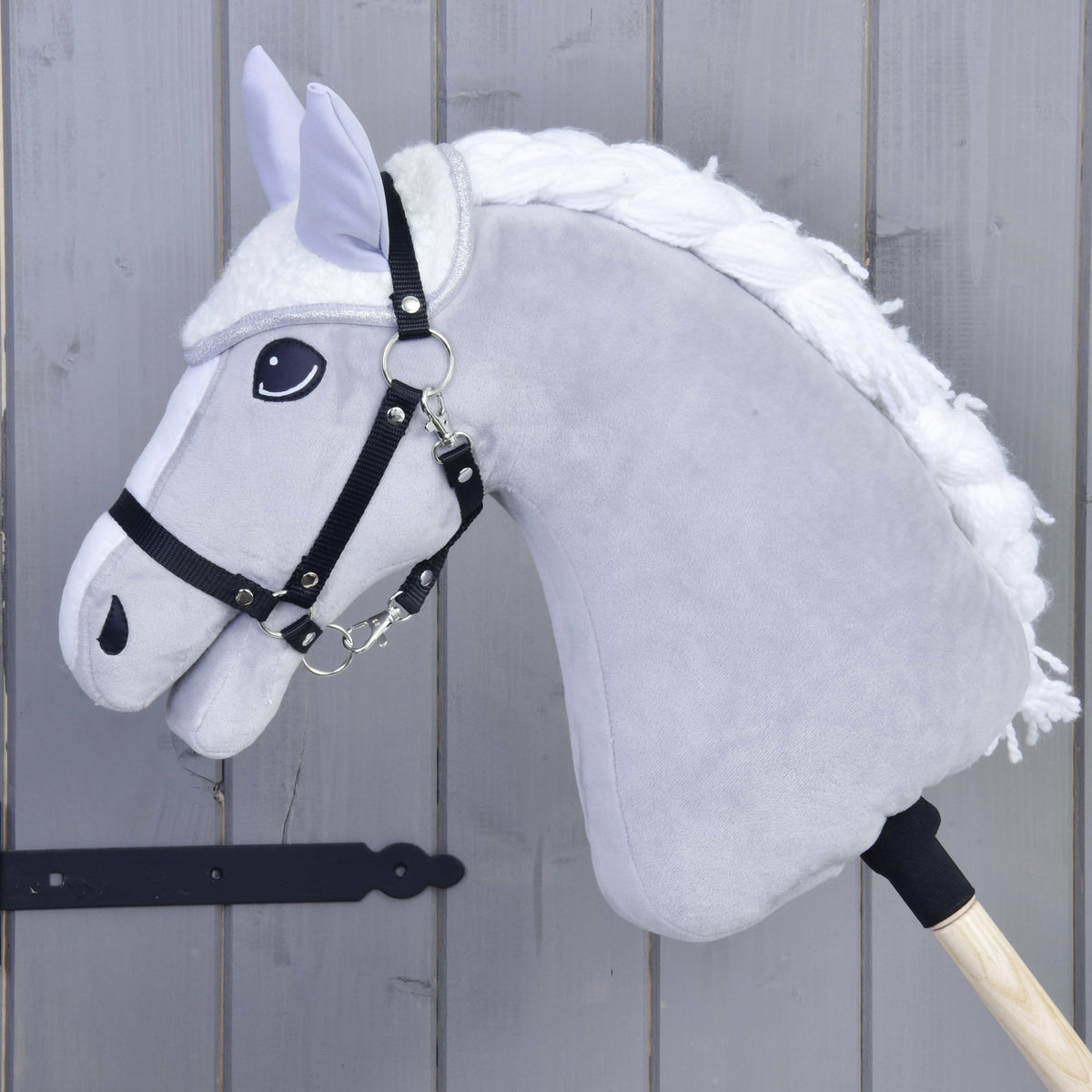 Detail Hobby Horse LarDen Set Snowflake so sivým telom, bielou hrivou, čiernou uzdečkou a opratami a čabrakou na drevenej tyči na pozadí sivého dreva.