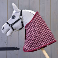 Hobby Horse LarDen "Set slávnostný Bordeaux" so sivým plyšovým Hobby Horse s čiernou uzdečkou a vínovo-ružovou dekou so vzorom kohútej stopy, nasadeným na drevenej tyči na pozadí sivých drevených dosiek.