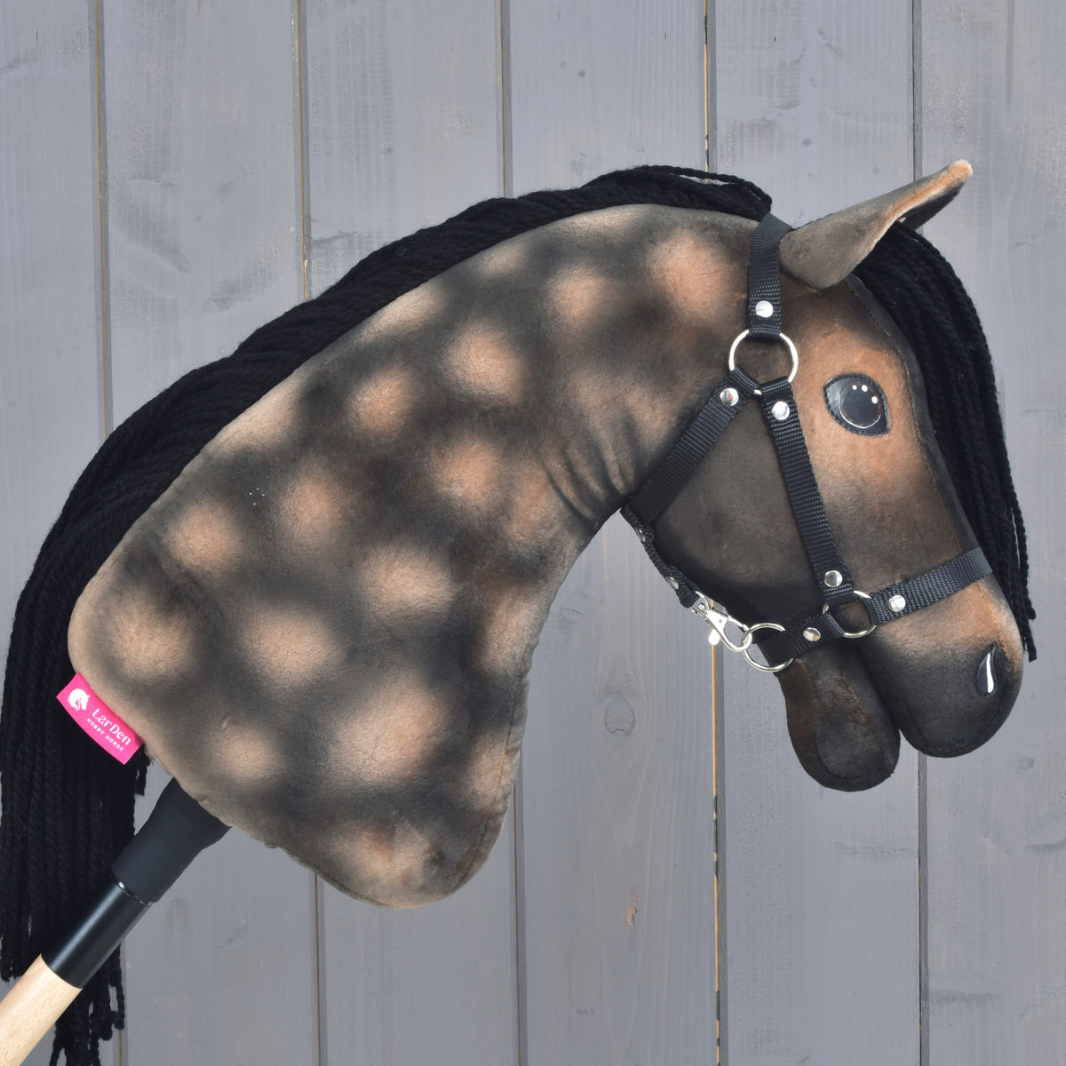Hobby Horse Stormy with Black Halter od Hobby Horse LarDen má grošovanú hnedo-čiernu plyšovú hlavu inšpirovanú hannoverským žrebcom, čiernu priadzovú hrivu a čiernu ohlávku na svetlom drevenom pozadí