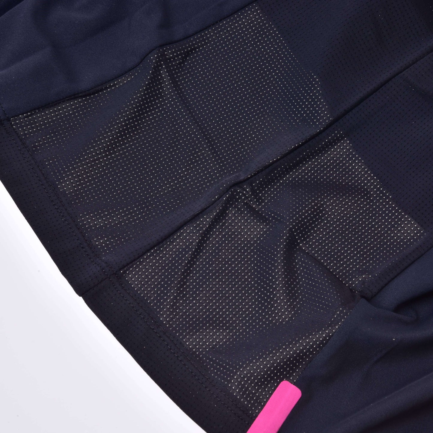 Detail Trika LarDen Active Black od Hobby Horse LarDen, zobrazující černou spandexovou tkaninu se síťovanými ventilačními panely a perforací pro prodyšnost; vpravo dole je částečně viditelný růžový štítek.