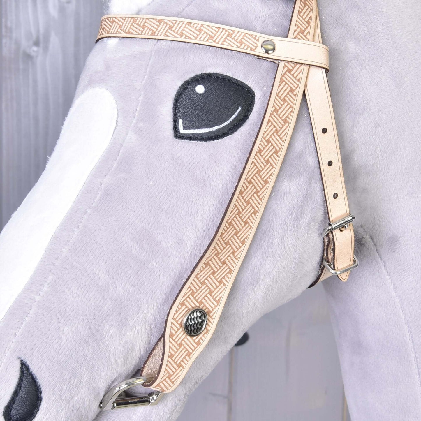 Detail Hobby Horse LarDen Uzdečky western Classic: štýlová svetlosivá plyšová konská hlava so vzorovanou béžovou uzdečkou a vyšívaným čiernym okom na svetlom drevenom pozadí.