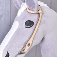 Detail hlavy plyšového koně ze světle šedé a bílé látky s vyšívaným černým okem a uzdečkou western jednouška od Hobby Horse LarDen se stříbrným kováním na dřevěném pozadí.