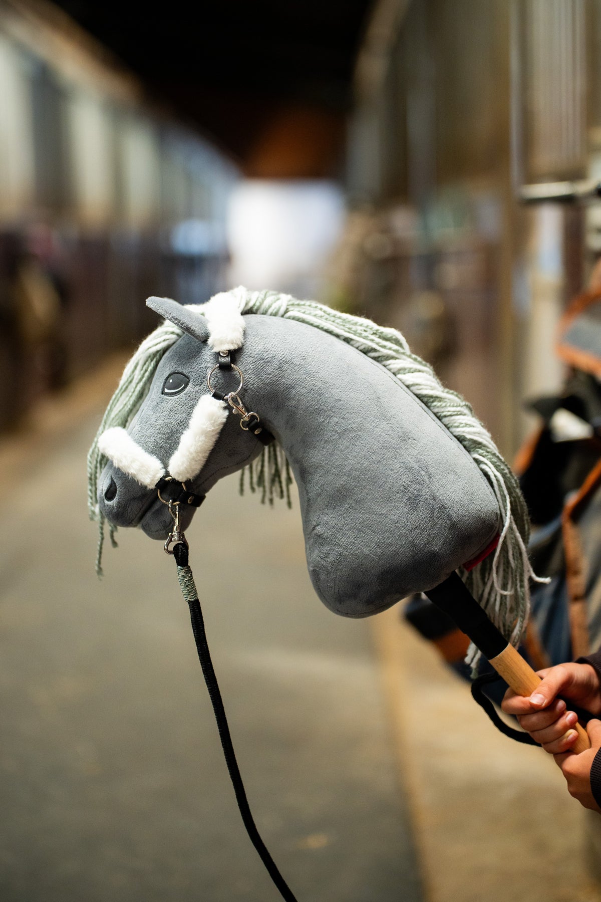Kožušinová ohlávka Hobby Horse Teddy Classic na sivej plyšovej hlave s lemom z bielej kožušiny a čiernym vodítkom