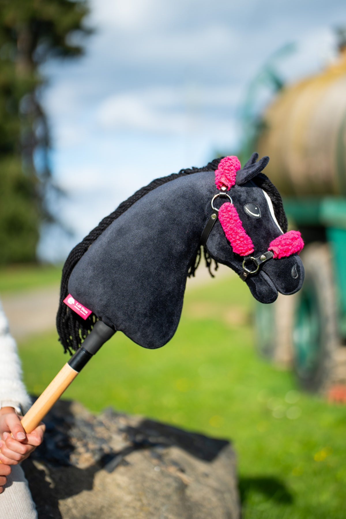 Hlava a krk Hobby Horse Cloony with Black Halter od Hobby Horse LarDen zdvihnuté proti zamračenej oblohe s čiernym plyšom, bielou hviezdou a čiernou priadzovou hrivou, s čiernou koženkovou ohlávkou s kompletnou ružovou kožušinou