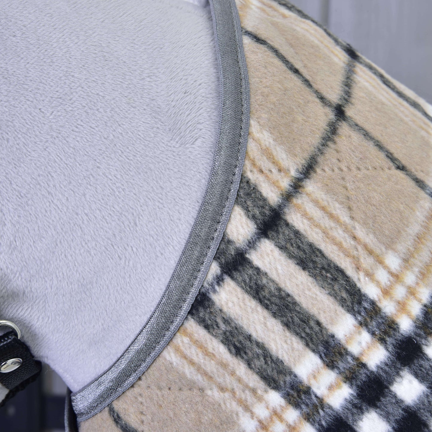Detail svetlosivého psa v Hobby Horse LarDen „Deka Cremo England“, béžovom, čiernom a bielom károvanom kabátiku so sivým lemovaním a čiernym pásikom so strieborným krúžkom pre extra ochranu pred hmyzom.
