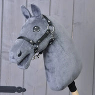 The "Build your horse" by related_to_12441055625556 features a plush dark grey head, light grey yarn mane, black bridle and reins, and is mounted on a wooden stick in front of gray wooden panels.