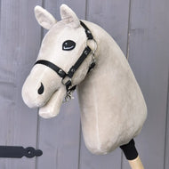 The "Build your horse" by related_to_12441055625556 is a beige tricolor faux fur custom hobby horse head with a black bridle on a wooden stick, shown against a gray wooden background.