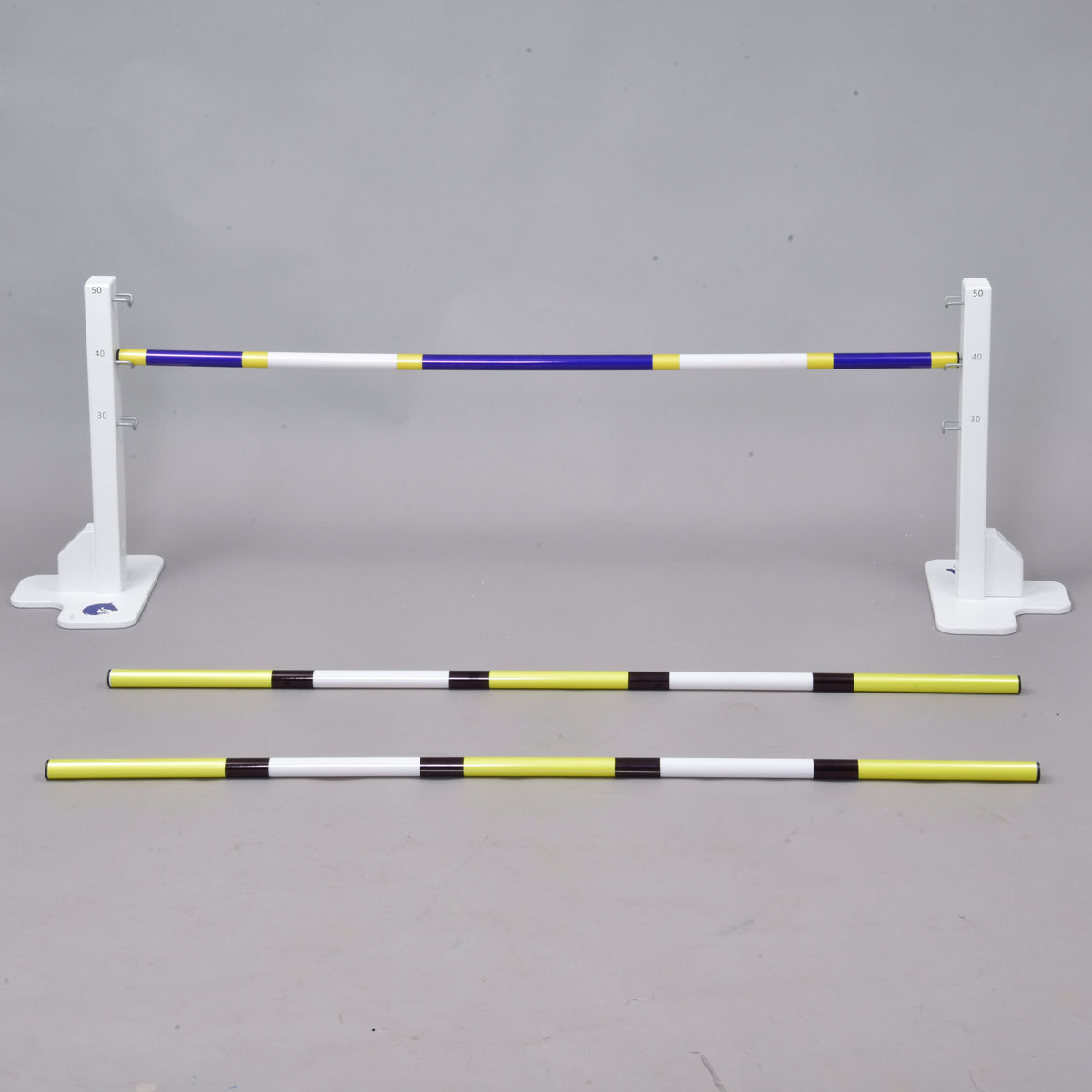 Set prekážky kolmák 50 cm + 2 ks bariérky od Hobby Horse LarDen obsahuje tri pruhované tyče – dve na zemi a jednu zdvihnutú – a poskytuje nastaviteľnú prekážku pre jazdecký tréning, dog agility alebo Hobby Horsing, vhodnú na použitie vnútri aj vonku.