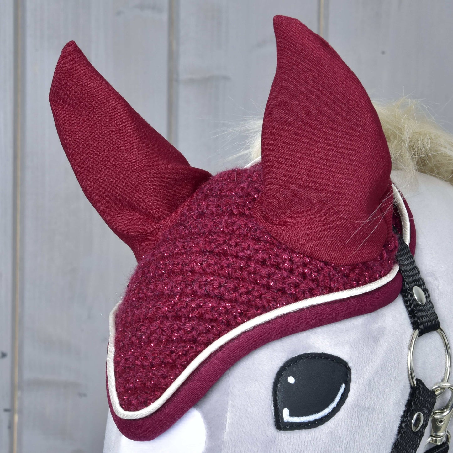 Čabraka Lux Maroon od Hobby Horse LarDen, detail zblízka s vysokými špicatými ušami a bielym lemovaním na bielom Hobby Horse na drevenom pozadí.