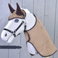 Set Manchester Le Chocolate od Hobby Horse LarDen s plyšovým Hobby Horse s bielou tvárou, čiernym postrojom, hnedými ušami a štruktúrovanou hnedou látkou na hlave a krku, doplnený Hobby Horse dekou, na drevenej tyči pred sivou drevenou stenou.