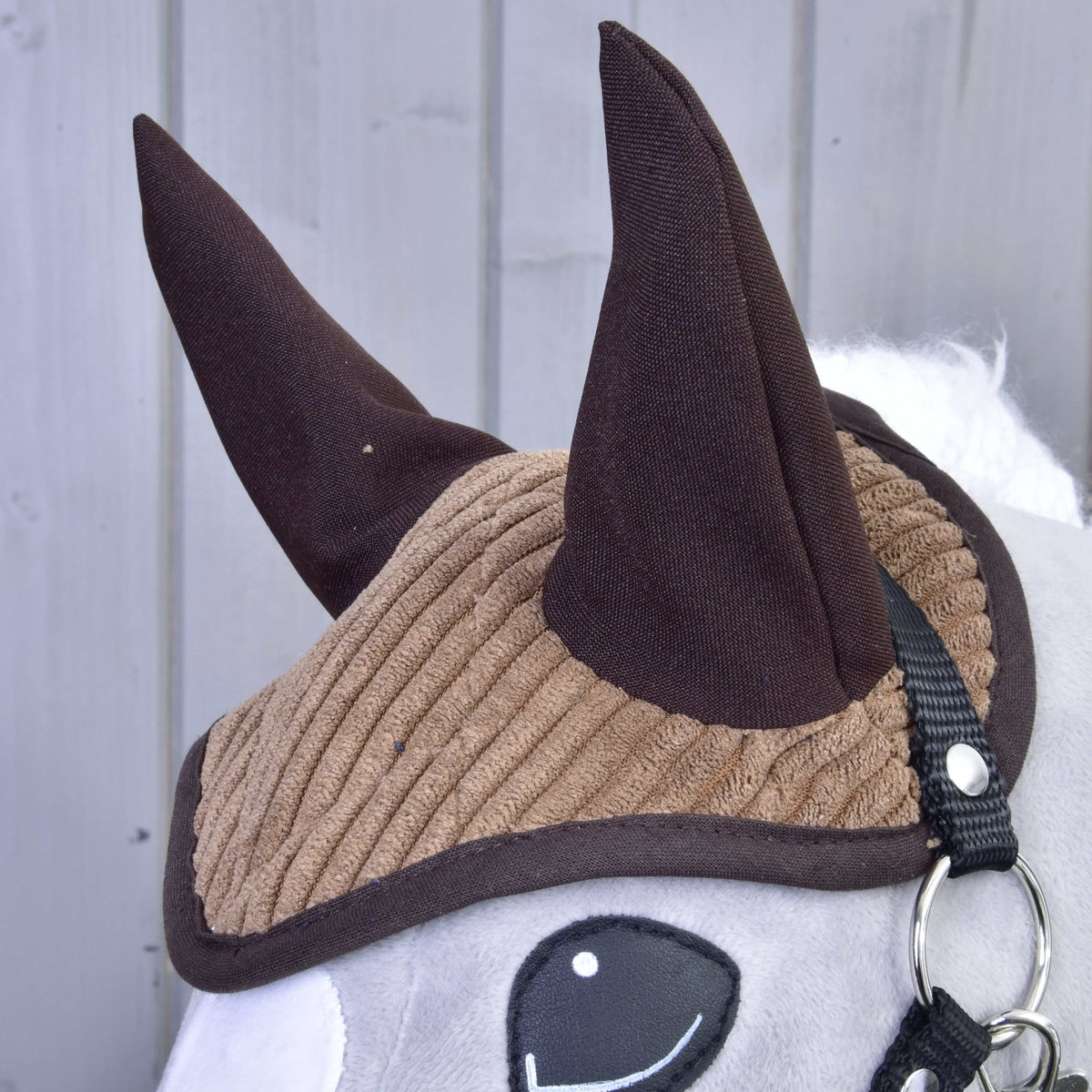 Set Manchester Le Chocolate od Hobby Horse LarDen, detail plyšovej hračky s hnedou rebrovanou čabrakou, tmavohnedými ušami, bielou tvárou, čiernou uzdečkou a jednoduchým vyšívaným okom – perfektný ako pôvabná dekorácia koňa.