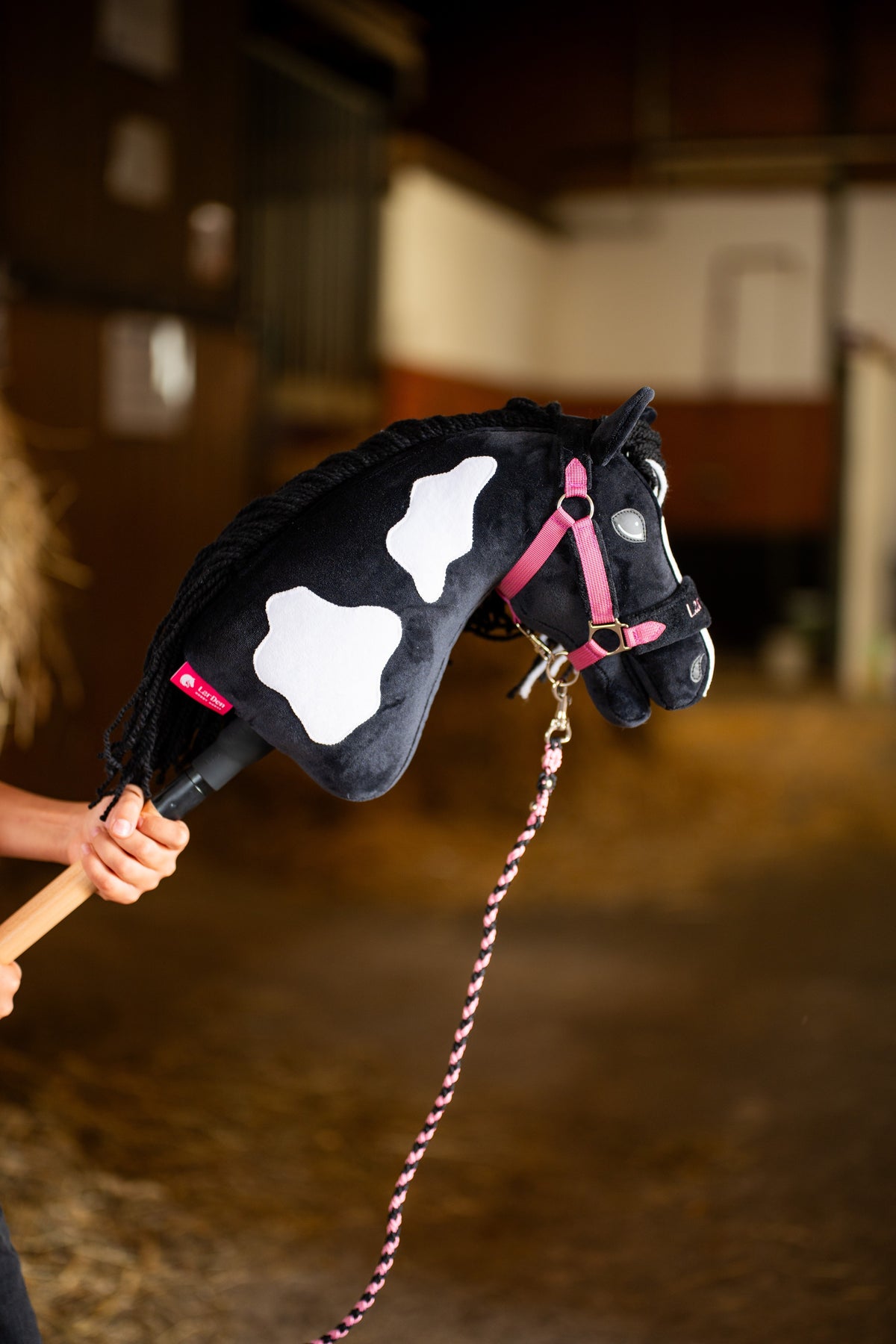 Hlava a krk Hobby Horse Merlin s Black Halter od Hobby Horse LarDen zdvihnuté v stajni – čierny plyš s bielymi škvrnami, čierna priadzová hriva – s ružovou súpravou LarDen Exclusive Pink a jej pleteným ružovým vodiacim lanom
