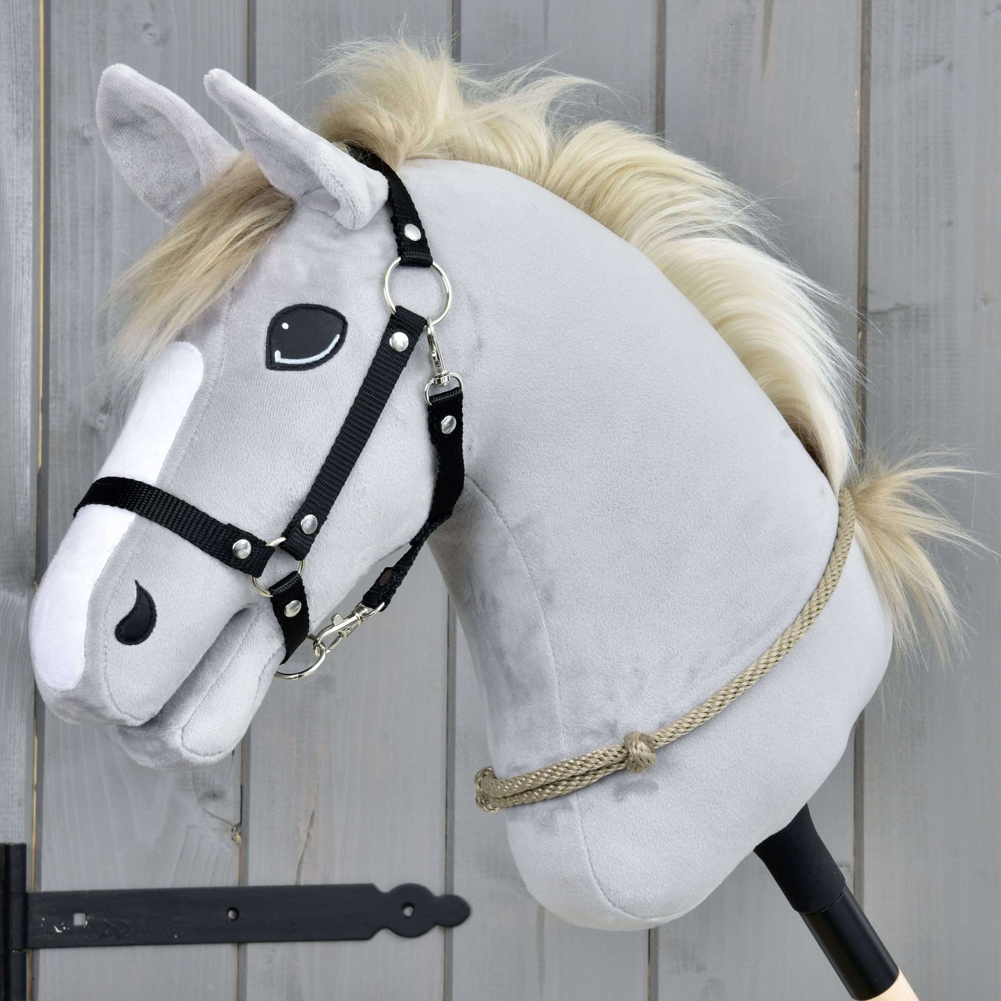 Hobby Horse LarDen Nákrčník Eleganza so sivou plyšovou hlavou, čiernou uzdečkou a béžovou hrivou na tyči, na pozadí drevených dosiek – ideálny na nácvik jazdenia bez uzdečky alebo techník cordero.