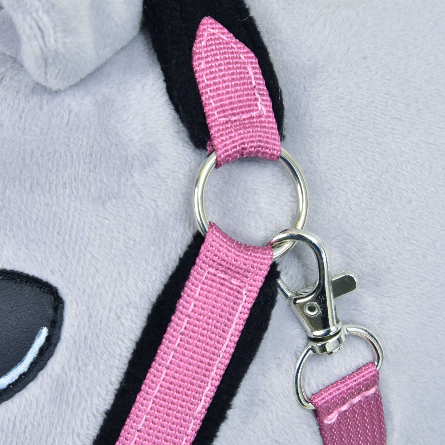 Ohlávka s barančekom LarDen Pink od Hobby Horse LarDen, detail svetlosivého plyšového povrchu, lesklého kovového krúžku na popruhu ružovej kožušinovej ohlávky, striebornej pracky a časti čiernoružového ucha s čiernym okom.