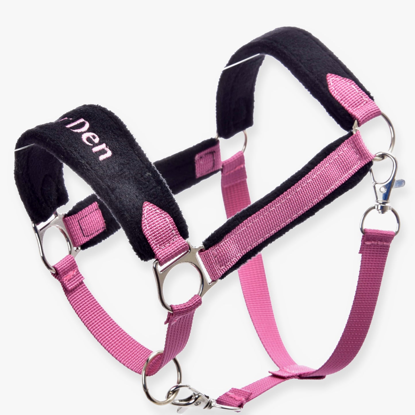Ohlávka s barančekom LarDen Pink od Hobby Horse LarDen v ružovej a čiernej farbe s kovovými krúžkami, nastaviteľnými popruhmi, mäkkým polstrovaním pre pohodlie, ružovými kožušinovými detailmi a čiastočne viditeľným nápisom „Den“ na nánosníku.