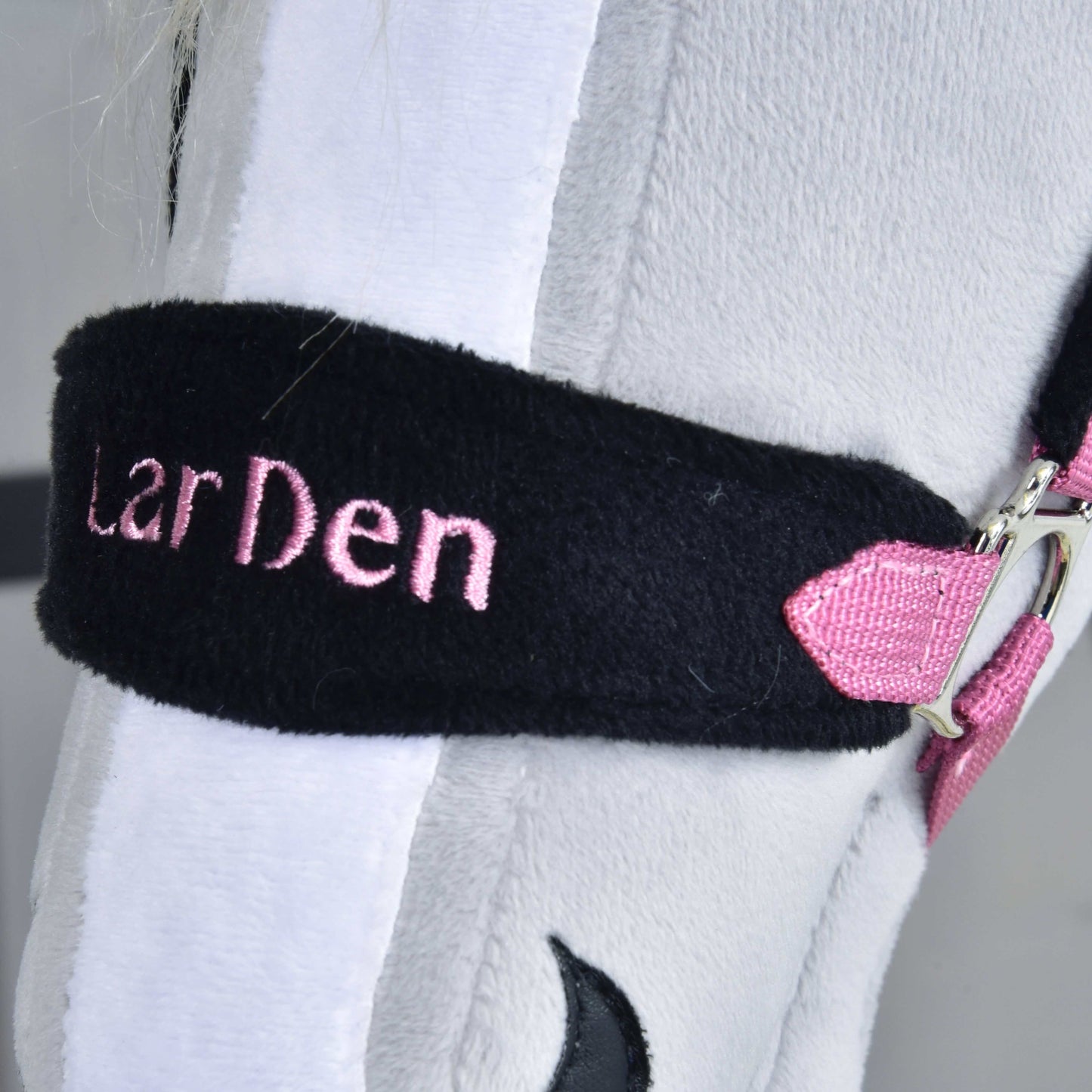 Ohlávka s barančekom LarDen Pink od Hobby Horse LarDen, detail ružovej výšivky na čiernom popruhu a ružovo-kovovej pracky na svetlosivom plyši – štýlová voľba pre tvojho Hobby Horse.