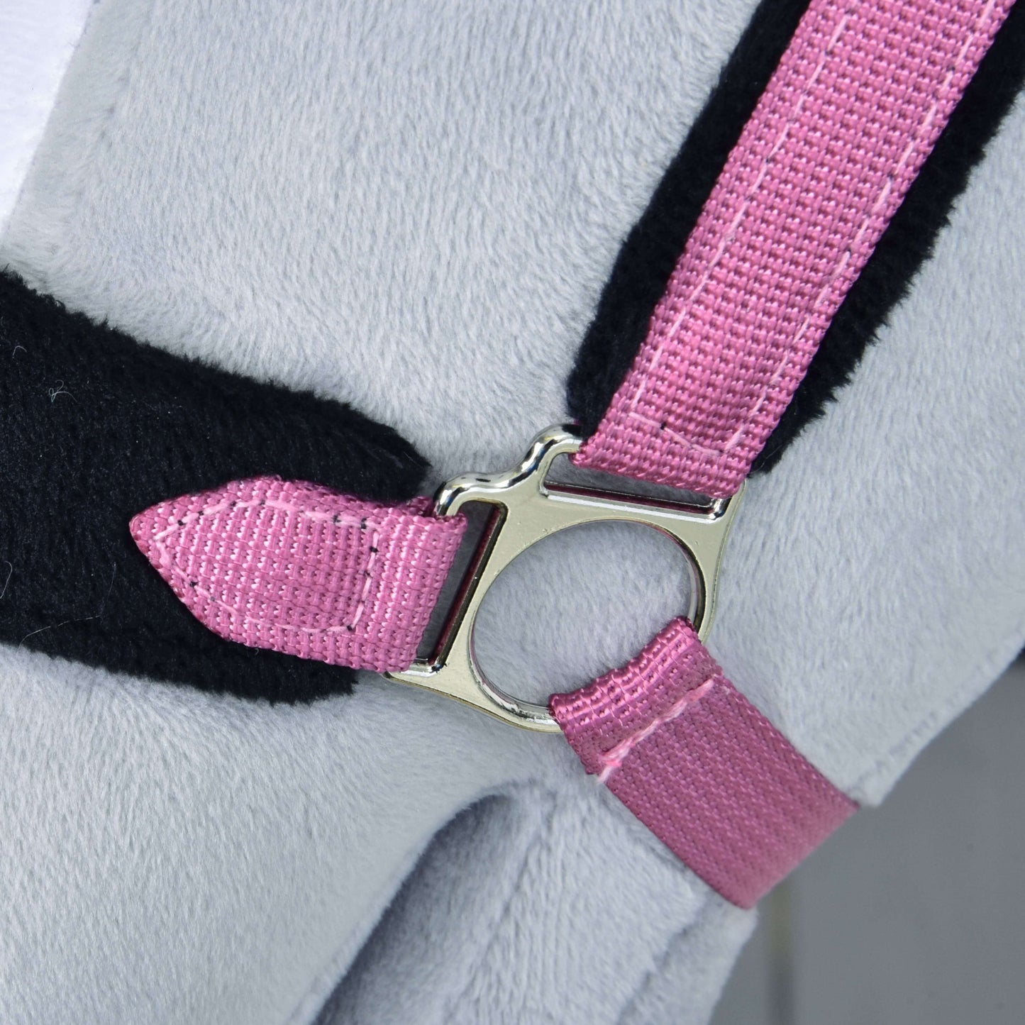 Ohlávka s barančekom LarDen Pink od Hobby Horse LarDen, detail ružového textilného popruhu s lesklou striebornou prackou na mäkkom svetlosivom povrchu, doplneného čiernym lemovaním.