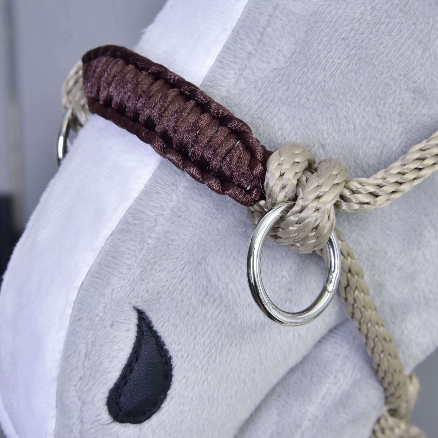 Detail tváre plyšového koňa s Parelka Nature od Hobby Horse LarDen s béžovo-hnedým pletením, kovovým krúžkom a čiernym vyšívaným detailom oka.