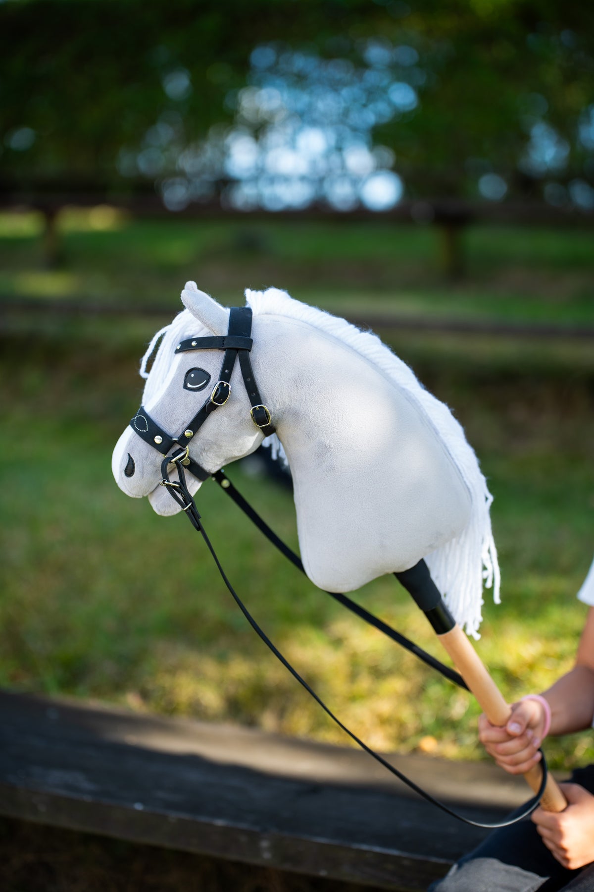 Kompletná bezudidlová uzdečka Hobby Horse zdobená na svetlosivom Hobby Horse vonku s čiernymi oťažami